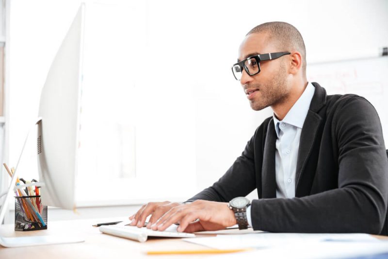 African American man with glasses typing on the computer